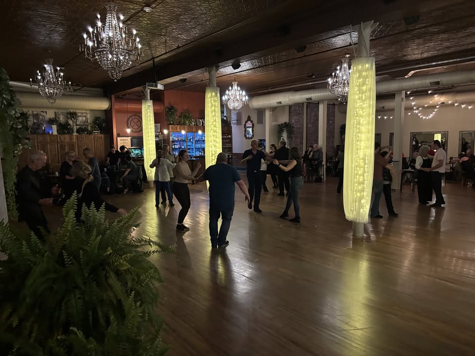 People dancing in a darkened dance hall.